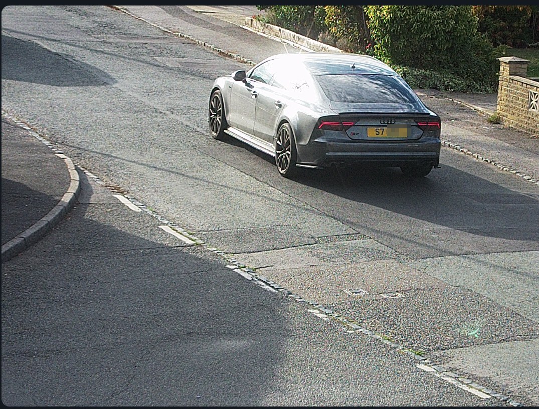 A real camera still of a grey Audi S7 on a residential road with its plate hidden, and a small live view of the same road in the corner
